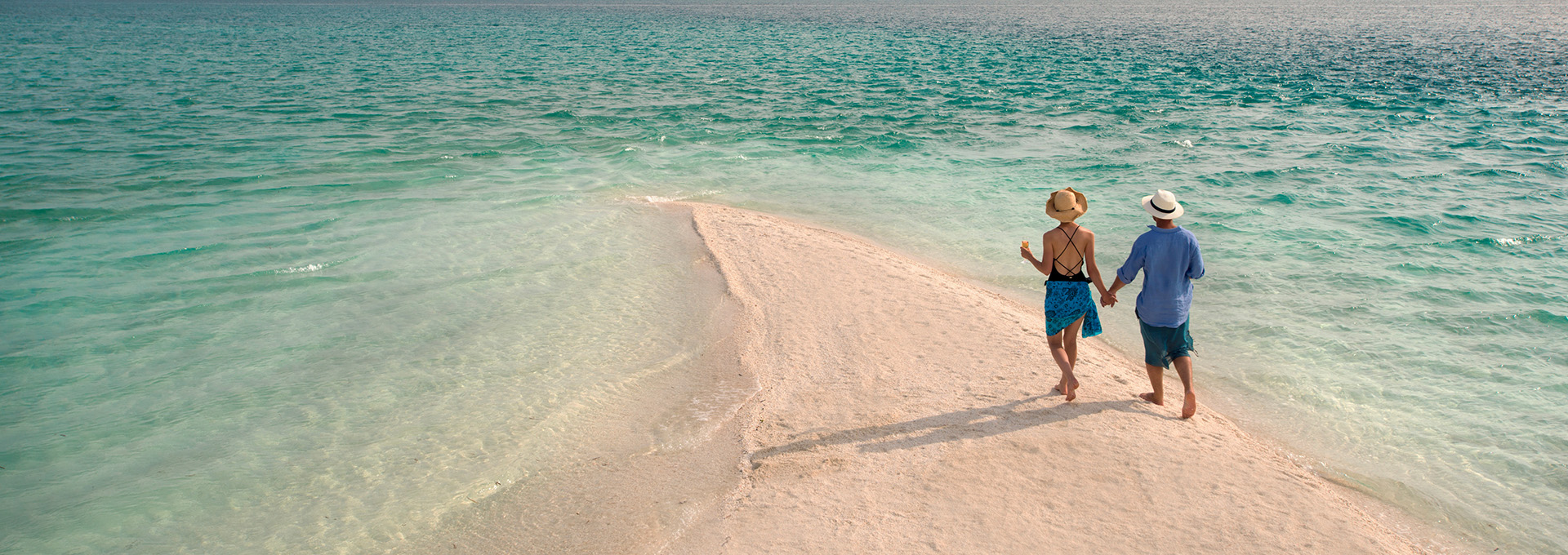Couple walking on a pristine Zanzibar sandbank at low tide